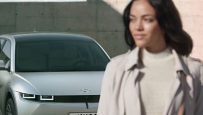 Žena odchádzajúca od svojho elektrického CUV strednej veľkosti Hyundai IONIQ 5 s trojrozmernou kapotou.