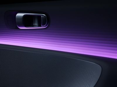 Výplň dverí a kľučka plne elektrického Hyundai IONIQ 6 s ambientným podsvietením vo fialovej farbe.
