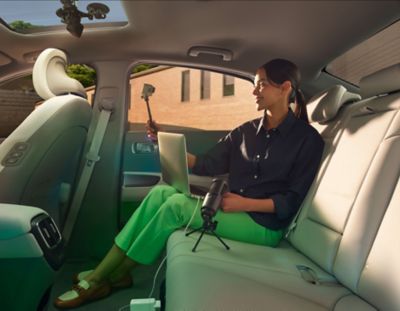 Zadné sedadlo štvordverového elektrického sedanu Hyundai IONIQ 6 s influencerkou používajúcou svoje kamerové vybavenie.