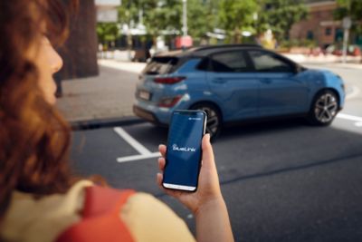 Žena používajúca aplikáciu Bluelink kráčajúca k svojmu novému modelu Hyundai Kona Electric.