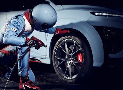 Muž v kombinéze N kontrolujúci pneumatiky Pirelli P Zero nového modelu Hyundai KONA N.