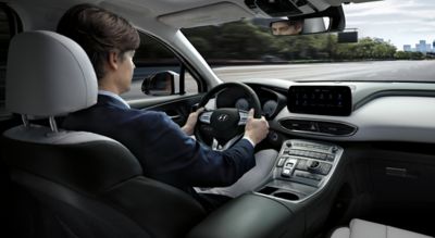 A man driving down the highway inside the new Hyundai SANTA FE Plug-in Hybrid 7 seat SUV.