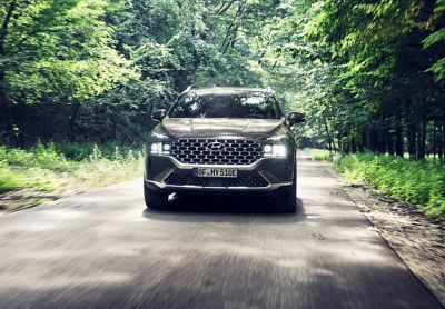 The new Hyundai SANTA FE Plug-in Hybrid 7 seat SUV driving on a forest road.