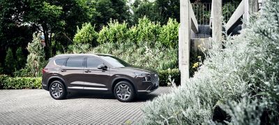 The new Hyundai SANTA FE Plug-in Hybrid 7 seat SUV parked in front of a modern house.