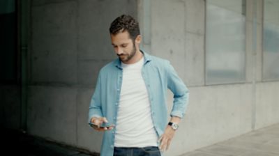 Muž stojaci na chodníku sa pozerá na mobilný telefón.