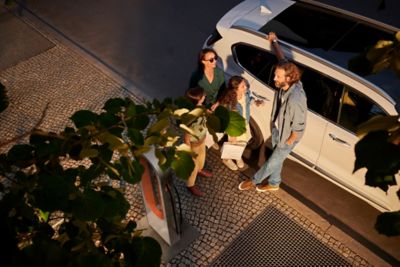 Rodina pri svojom elektrickom vozidle Hyundai EV chystajúca sa nabíjať ho zelenou energiou.