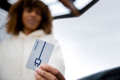Žena ukazujúca kartu Charge my Hyundai pre jej elektrické vozidlo.
