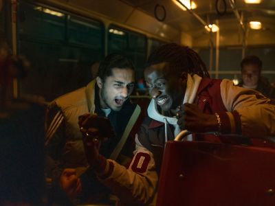 Football fans on a bus celebrating while watching football on their smartphone.