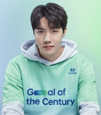 Člen BTS J-Hope má oblečený zelený dres Team Century a na ňom sivú mikinu.